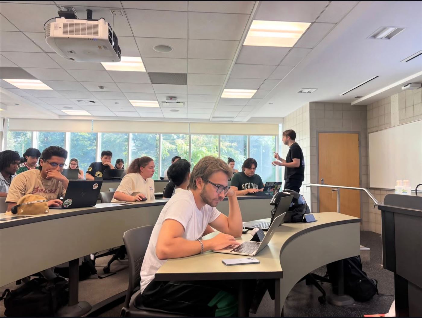 Excel Club members working on laptops while a lead teaches at the front of the room
