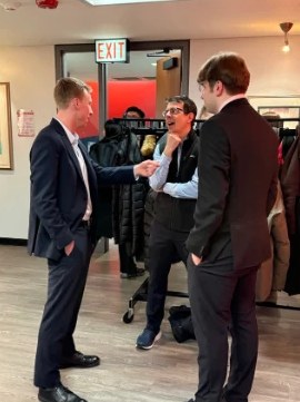 A student in a suit chatting with two professionals at Networking Night